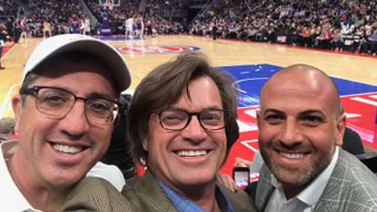 Three men are taking a picture together at an nba game.