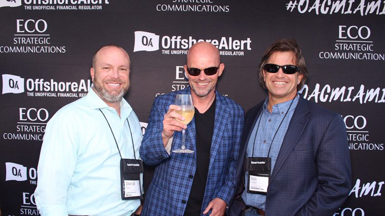 Three men holding a glass of wine at an event.