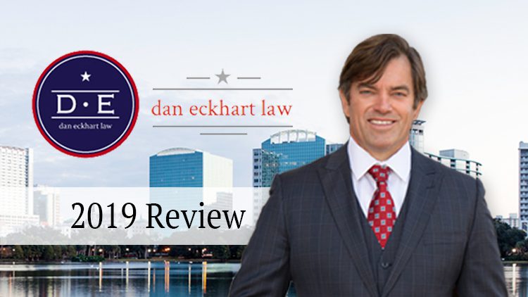A man in suit and tie standing next to the words " dan eckhart law."