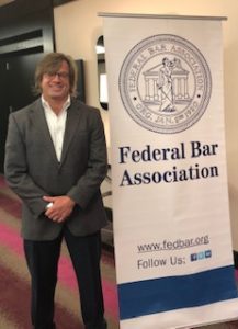 A man standing next to a federal bar association sign.